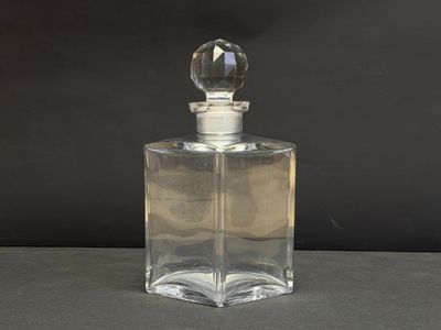 une photo d'un flacon de parfum en verre transparent posé sur une table