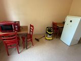 a room with a table, chairs, a refrigerator and a microwave