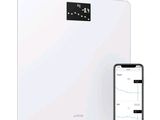 a close up of a smart scale with a cell phone next to it