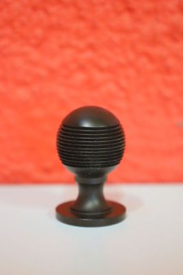 un bouton noir posé sur une table blanche, avec un mur rouge en arrière-plan