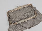 an old silver mesh purse sitting on top of a white table