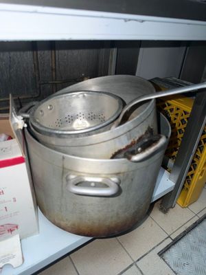 Des casseroles et des poêles sont empilées sur une étagère dans une cuisine.