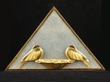 deux oiseaux dorés posés sur une assiette dorée devant un fond noir