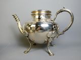 a silver tea pot on a stand on a table