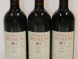 trois bouteilles de vin rouge sont alignées sur une surface blanche