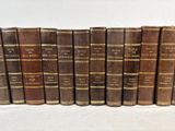 several old books are lined up in a row on a white surface