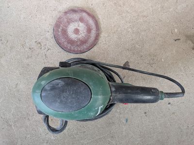a green and black blow dryer sitting on the ground