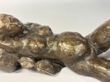 a bronze statue of a woman laying on her stomach