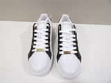 white and black sneakers with gold details on them on a white surface