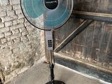 un ventilateur posé par terre devant un mur de briques