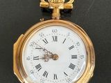 a gold pocket watch with roman numerals on the face