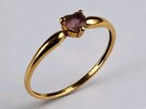 gros plan d'une bague en or avec une pierre rose