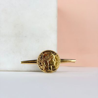 une bague en or surmontée d'une pièce de monnaie, posée sur un bloc de marbre