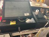 une caisse enregistreuse posée sur un bureau, à côté d'un rouleau de papier toilette