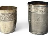 deux tasses en argent posées l'une à côté de l'autre sur une surface blanche