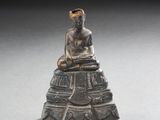 une image représentant une statue d'une personne assise sur un rocher