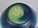 a blue and green vase with a leaf on it