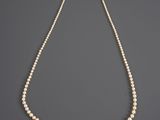a white pearl necklace with a gold clasp on a gray background