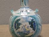 a blue and white vase with a picture of a house on it