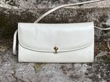 beige leather handbag with a metal clasp on a stone surface