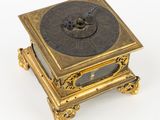 une horloge posée sur un support sur une surface blanche