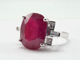 un gros plan d'une bague ornée d'une pierre rouge sur un fond blanc