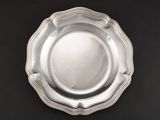 une assiette en argent posée sur une table noire, sur fond noir