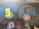 two blue fan sitting on top of a table next to each other