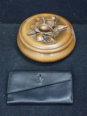 un sac à main noir et un plateau doré orné d'une rose