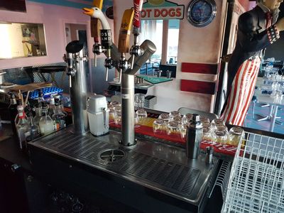a man that is standing behind a bar with a bunch of drinks