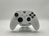 a close up of a game controller on a stand on a white surface