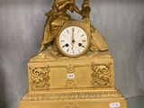 une horloge en or posée sur une étagère en verre dans une pièce