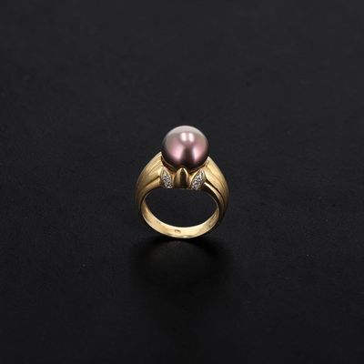 a pink pearl and diamond ring on a black surface