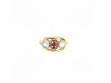 un gros plan d'une bague en or sertie d'une pierre rouge et blanche