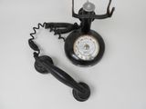a black telephone with a clock on it next to a cord