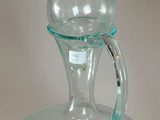 a clear glass bottle with a handle on a table