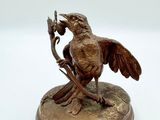 statue représentant un oiseau perché sur une branche, une fleur dans le bec
