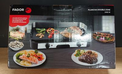emballage représentant une boîte noire et blanche avec l'image d'un barbecue et d'assiettes de plats posées sur une table