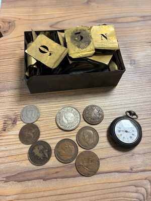 une boîte de pièces de monnaie et une montre de poche posées sur une table