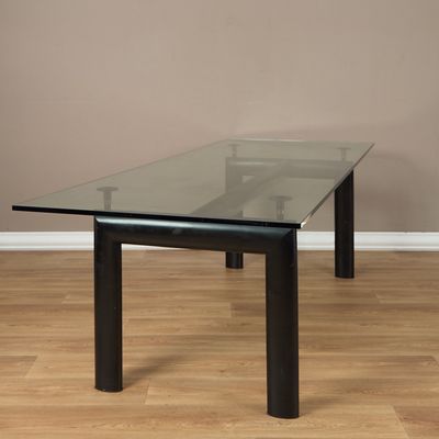 une photo d'une table en verre aux pieds noirs posée sur un parquet
