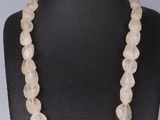 un collier composé de perles de quartz blanc enfilées sur un mannequin noir