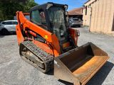 un petit tracteur orange garé sur un parking