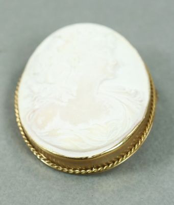 un gros plan d'une broche blanche et dorée posée sur une surface grise