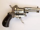 un vieux revolver avec une poignée en bois sur une surface blanche