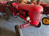 a red tractor parked in a garage with other tractors