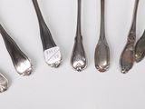 several spoons and forks are lined up on a white surface