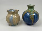 two vases sitting next to each other on a white surface