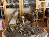 statue of a dog and a cat on a table in front of a bookshelf