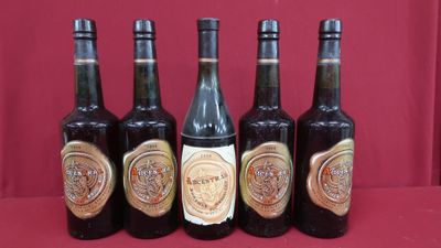 six bottles of wine are lined up on a red surface