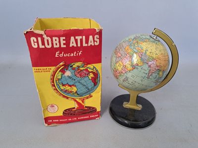 a small globe on a stand next to a box of books